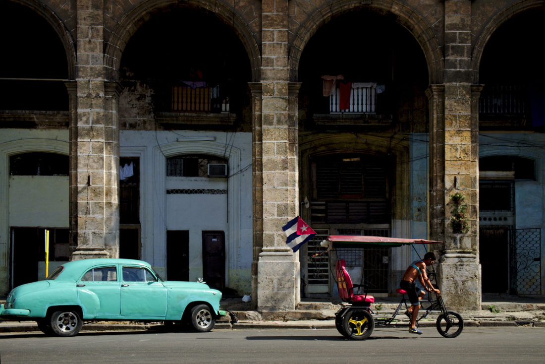 An old green car parked outside the big arcades that are só typical of Centro Habana.